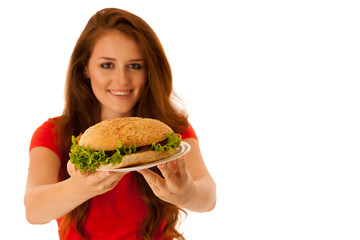 Unhealthy meal - happy young woman eats hamburger isolated over white