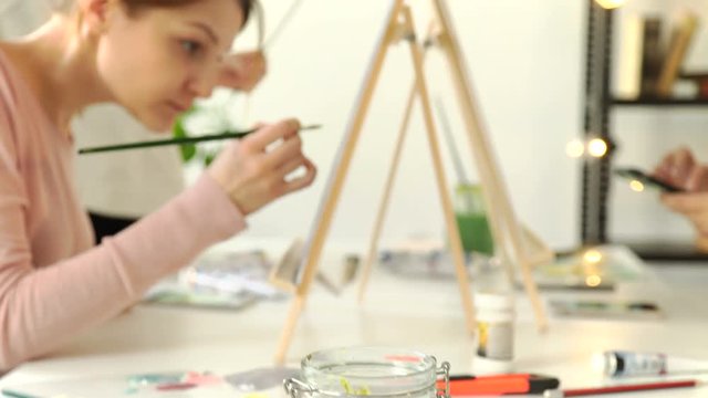 Creative contemporary painter paints a colorful abstract painting. Closeup of painting process in art workshop. Creative positive woman painter paints in her studio colorful abstract painting. 4k 20s