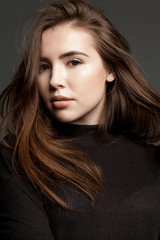 Naklejka premium Portrait of a young girl model with clear skin, flying hair looking at the camera.
