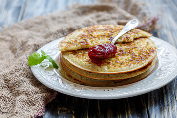 Stack of pancakes and teaspoon with berry jam.