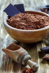 Wooden bowl with the cocoa powder and dark chocolate.