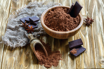Cocoa powder and dark chocolate in a wooden bowl.