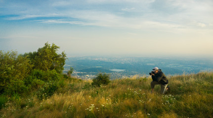 Fototapeta na wymiar Photographer takes pictures at the meadow on the top of Italian mountains