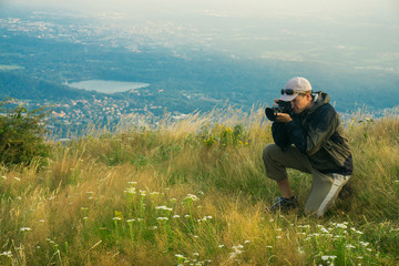 Fototapeta na wymiar Photographer takes pictures at the meadow on the top of Italian mountains