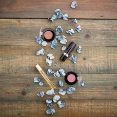 Flat lay, top view. Feminine desk workspace with cosmetics, lipstick and blue flowers on wood background. Woman background.