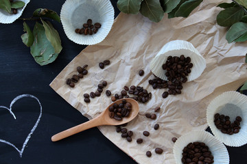 spilled coffee beans on brown paper on a black table with hearts