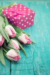Bouquet of Tulips and gift box on turquoise rustic wooden background with copy space for message. Spring flowers. Greeting card for Valentine's Day, Woman's Day and Mother's Day holidays. Soft focus.