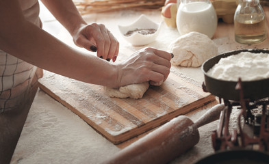 Close up of female baker hands kneading dough and making bread
