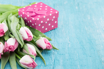 Bouquet of Tulips and gift box on turquoise rustic wooden background with copy space for message. Spring flowers. Greeting card for Valentine's Day, Woman's Day and Mother's Day holidays. Soft focus.