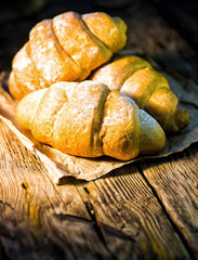 Tasty buttery croissants on old wooden table.