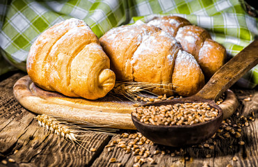 Tasty buttery croissants on old wooden table.