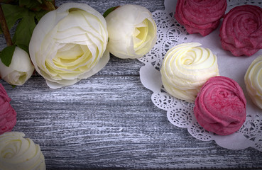 White buttercup flowers ranunculus white and pink zephyr marshmallows lacy paper napkin on gray wooden background. Copy space.