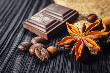 Chocolate bar and spices on wooden table, close up