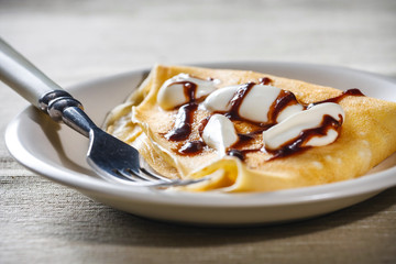Crepe with whipped cream and chocolate sauce