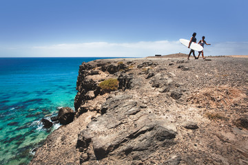 guys with a surboard walking on a Cliff in Fuerteventura.