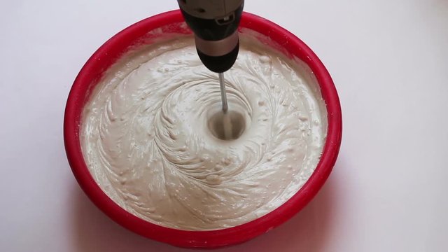 Builder blends liquid putty spackling in container with mixer for construction works