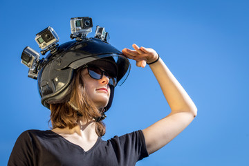 Une jeune femme regardant l'horizon, porte un casque avec quatre caméras de sport fixées dessus