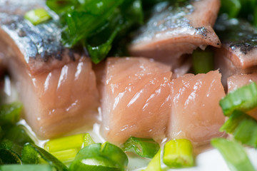 Sliced herring with green onion on a plate. Selective focus macro shot with shallow DOF.