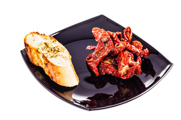 Dried Tomatoes on a black plate on white