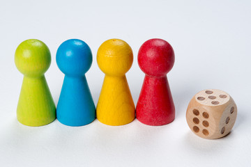 Colored pawns and dice, working together conceptual on wood table