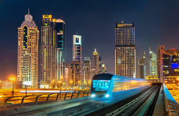 Fototapeta premium Samojezdny pociąg metra z wieżowcami w tle - Dubaj, Zjednoczone Emiraty Arabskie