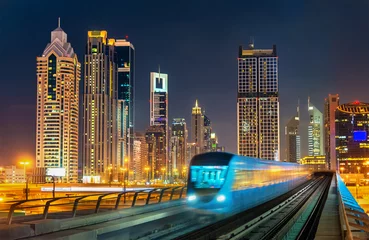 Foto auf Glas Selbstfahrender U-Bahn-Zug mit Wolkenkratzern im Hintergrund - Dubai, Vereinigte Arabische Emirate © Leonid Andronov