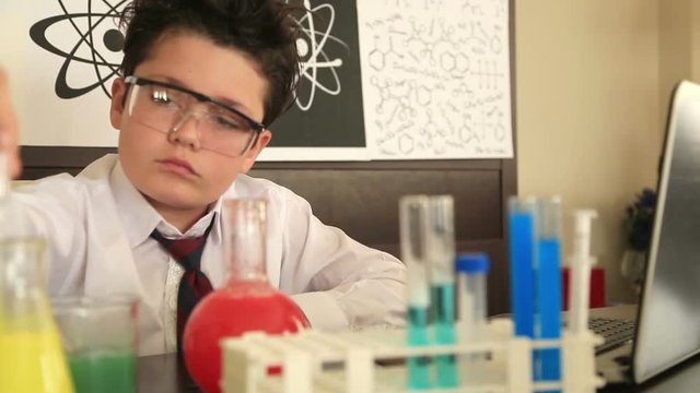 Cute schoolboy making science experiments with lab equipment at school