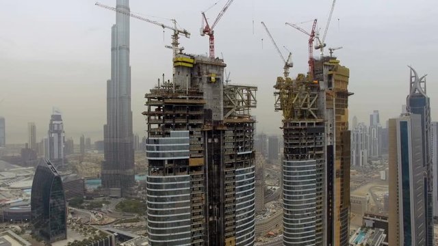 aerial view of several skyscrapers under construction with scaffolding and cranes. Dubai, UAE