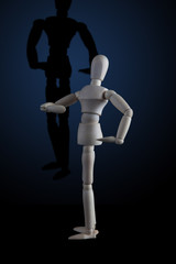Wooden figurine flexing muscles in bodybuilder pose with shadow on dark background
