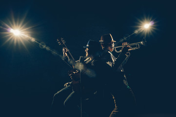 Musician Duo band playing a Trumpet and singing a song and playing the guitar on black background...