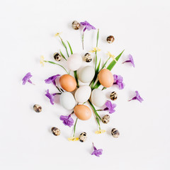 Easter eggs, quail eggs, yellow and purple flowers on white background. Flat lay, top view. Traditional spring concept. Easter concept.