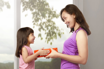 Smiling mother and daughter with gift box © Leo Lintang