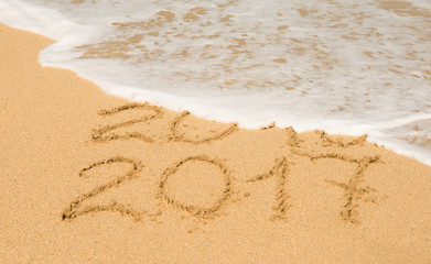 digits  2016 and 2017 on the sand