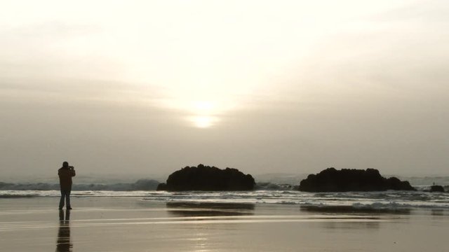 Silhouetted person taking a photo at the beach on the Pacific Northwest Coast in Oregon