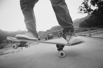 young skateboarder legs practice ollie at skatepark ramp