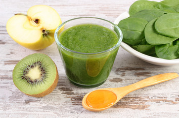 Ingredients and fresh cocktail from spinach, apple and kiwi on wooden background, healthy nutrition