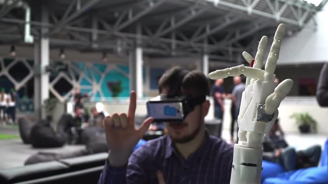 Ufa/Russia - 24 march 2016: Cybernetic robot arm, which controls people. Man controls robotic arm through virtual reality glasses. Playing game or the game lives in another world. Hand as the Skynet