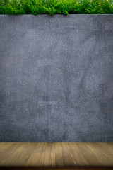 Wooden table with concrete wall or marble wall and ornamental plants or ivy or garden tree for background.