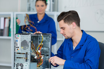 team of students examining and repairing computer parts