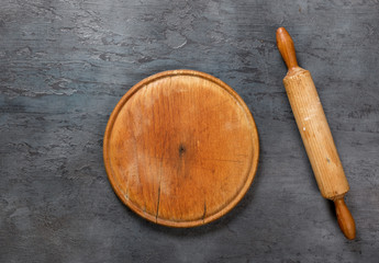 Wooden board with rolling pin on the dark stone surface