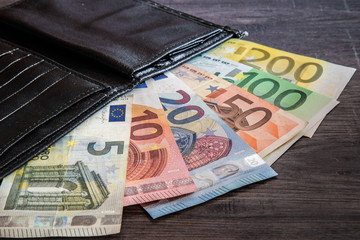 Euro money with black wallet on the wooden table. Dealing with money.