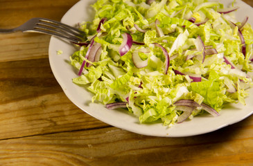 Salad with chinese cabbage and onion on wooden table