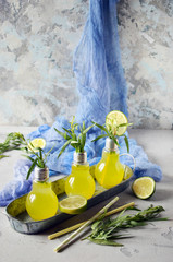 Fresh lime and lemon lemonade with estragon in a glass on a light grey desk