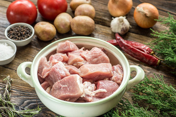 Raw pork ham with vegetables and spices on a wooden cutting board