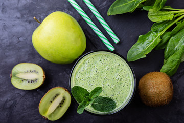 Healthy green smoothie with spinach and kiwi in a glass, top view