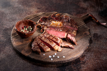 Medium rare grilled beef steak ribeye on a brown rusty background