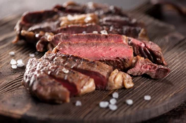 Foto op Plexiglas anti-reflex Steakhouse Gesneden medium zeldzame gegrilde biefstuk ribeye close-up op een bruine roestige achtergrond