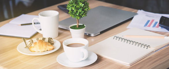 Business workplace and business objects such as laptop, note book, calculator, pen, a cup of coffee, flower, bread, image bar graph etc.Focus cup of coffe