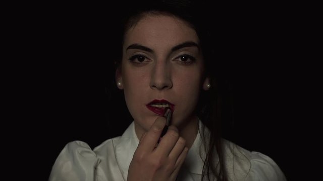 Woman Paints Her Lips With Lipstick On A Black Background