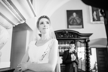 Happy and lovely wedding couple at ancient museum room with big stone fireplace. Bride on focus. Black and white.